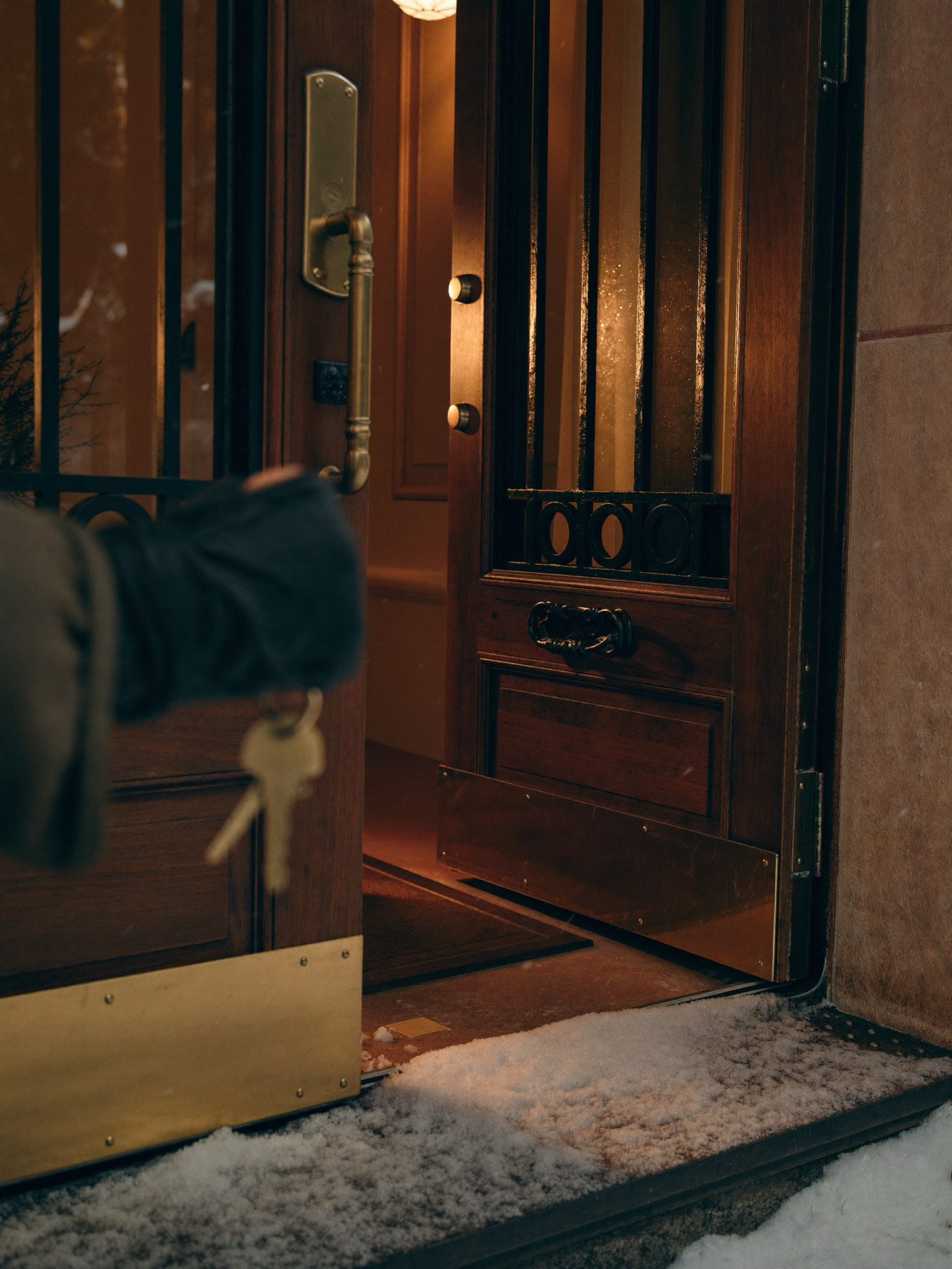 Keys in hand at the warm entry of an alpine estate in falling snow